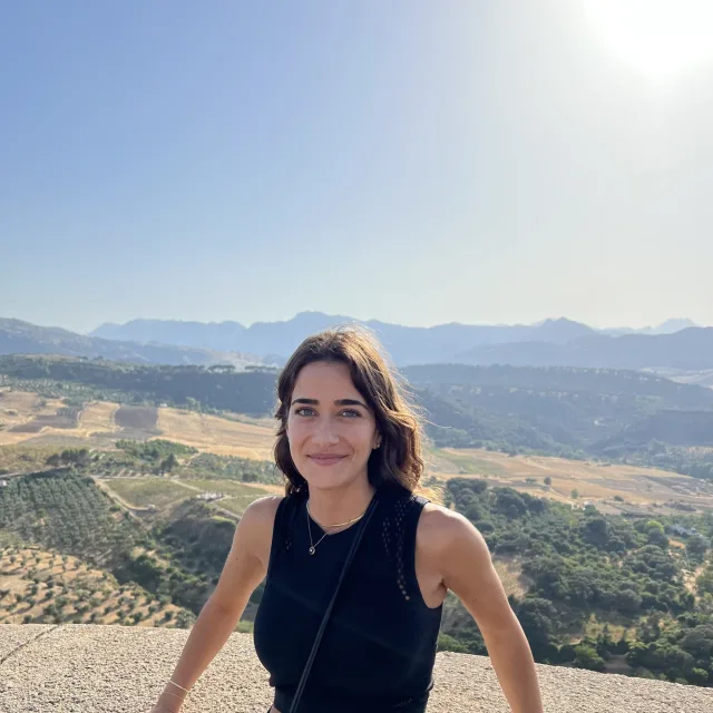 Travel advisor Deemah Bader in a black tank top smiling in front of a sunlit valley