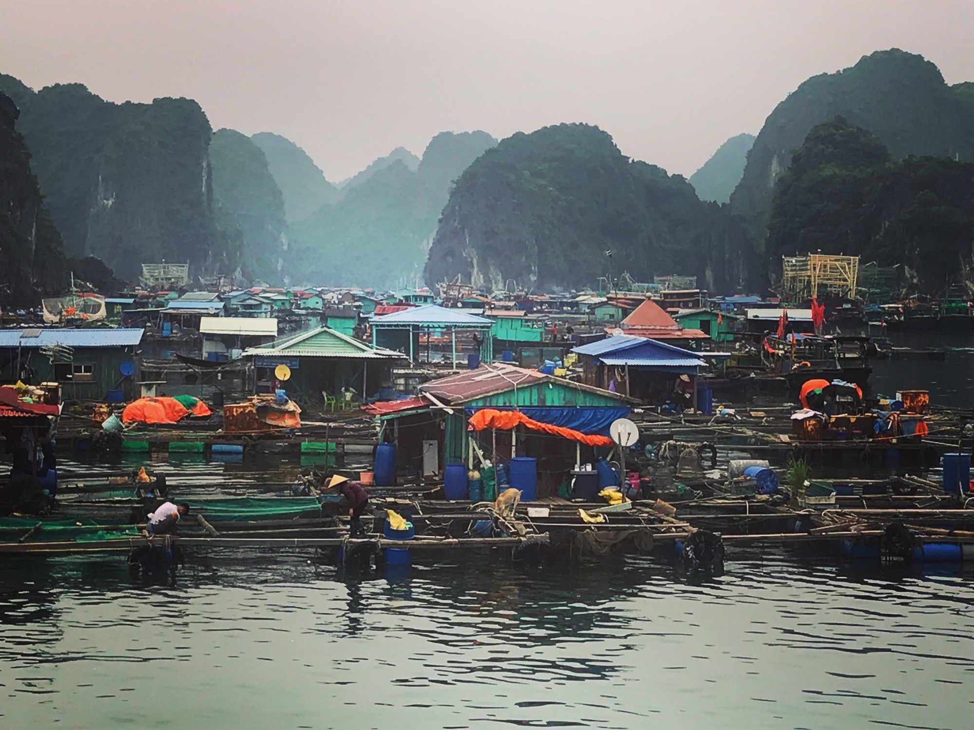 Water body with small colorful cabins and mountains at the back.