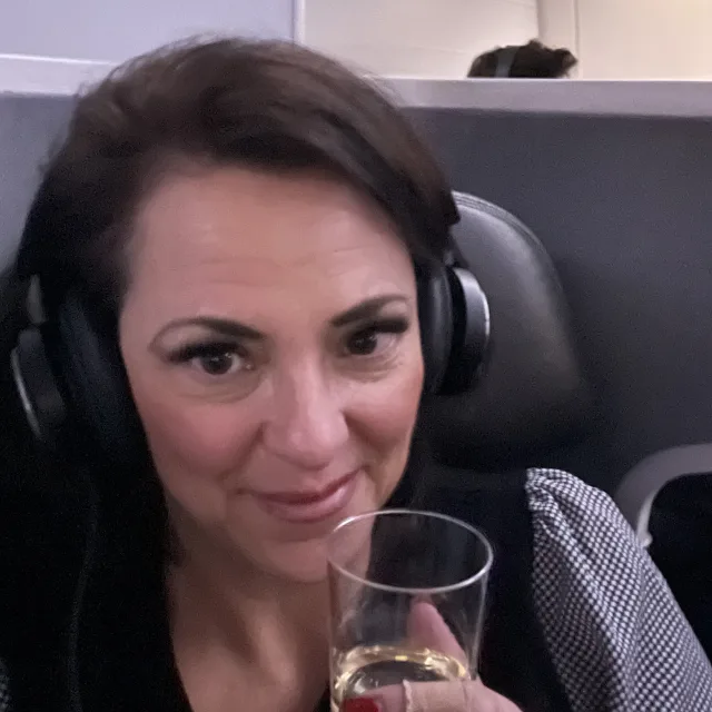 Travel Advisor Jeni Stivale on a plane with a glass of champagne.