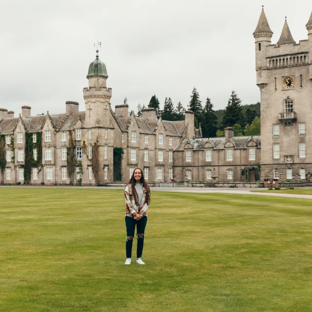 A stunning woman exudes grace in front of a castle