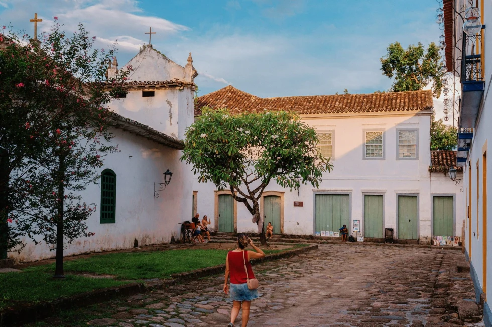 An old white church with people in the courtyard.