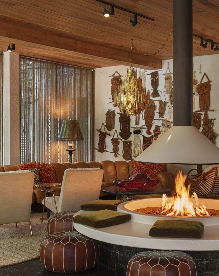 a round fire pit surrounded by leather stools in a room with eclectic artwork