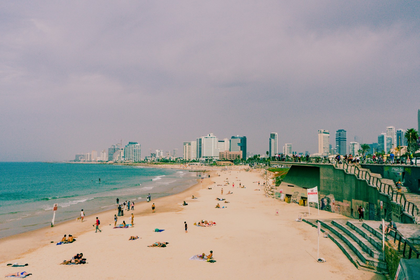 Beach with water with city in the background on a cloudy day