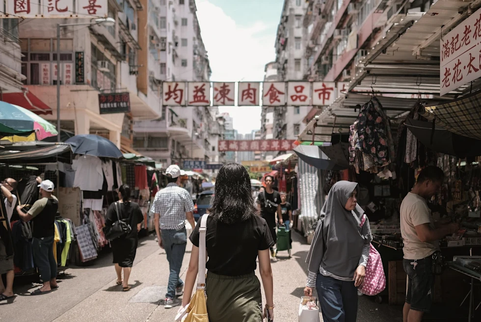 A street market with people walking and shopping from stalls.