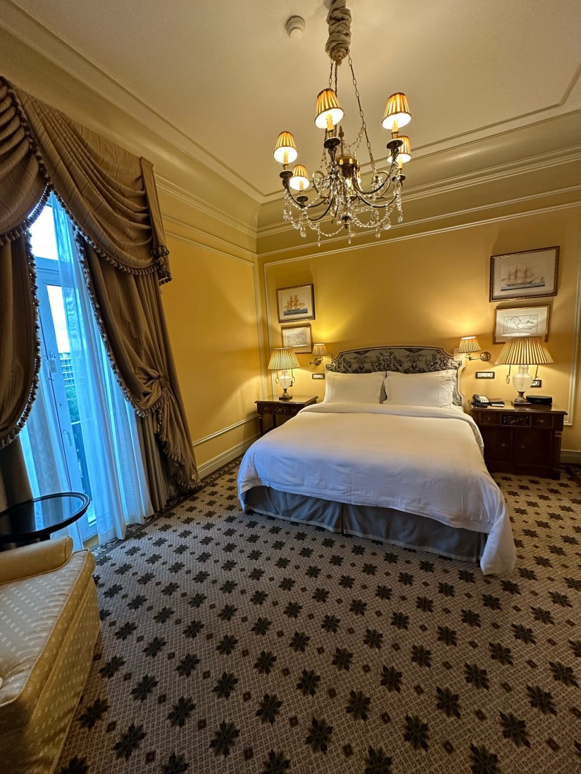 An elegant hotel bedroom at Hotel Grand Bretagne with chandelier and patterned carpet