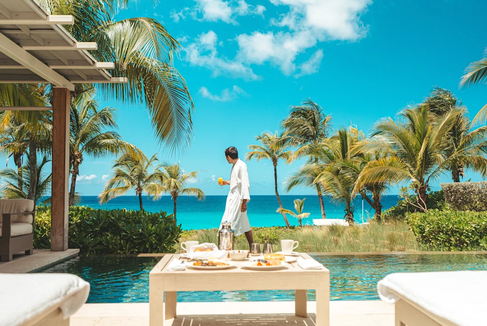 man standing near table of food with palm trees in the background