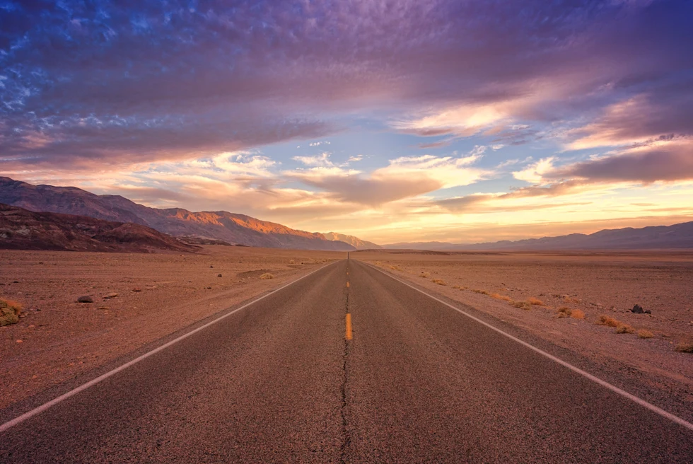 road surrounded by desert during sunset