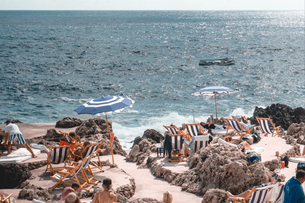 people among blue and white striped chairs on a beach 