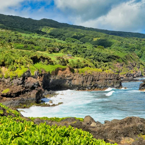 Body of water next to cliffs and green mountains during daytime