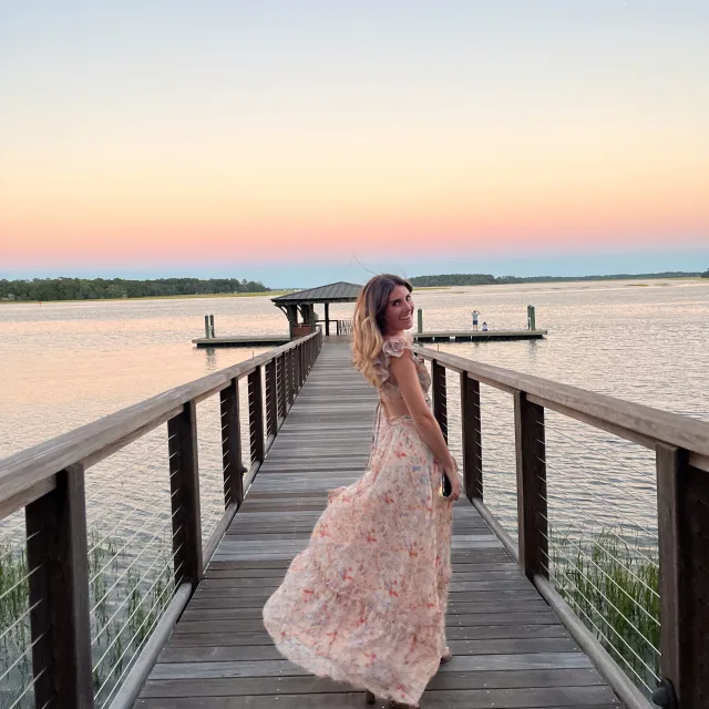 Picture of Shelby wearing a dress on a dock with a lake view at sunset