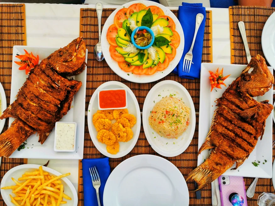 A table with two fish dishes and plantains. 
