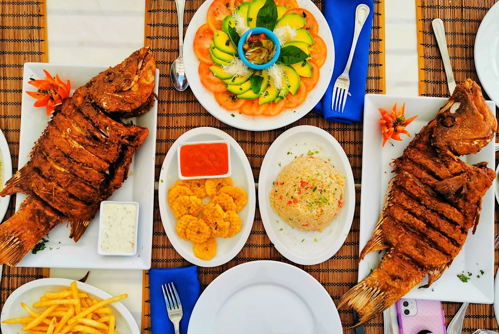 A table with two fish dishes and plantains.