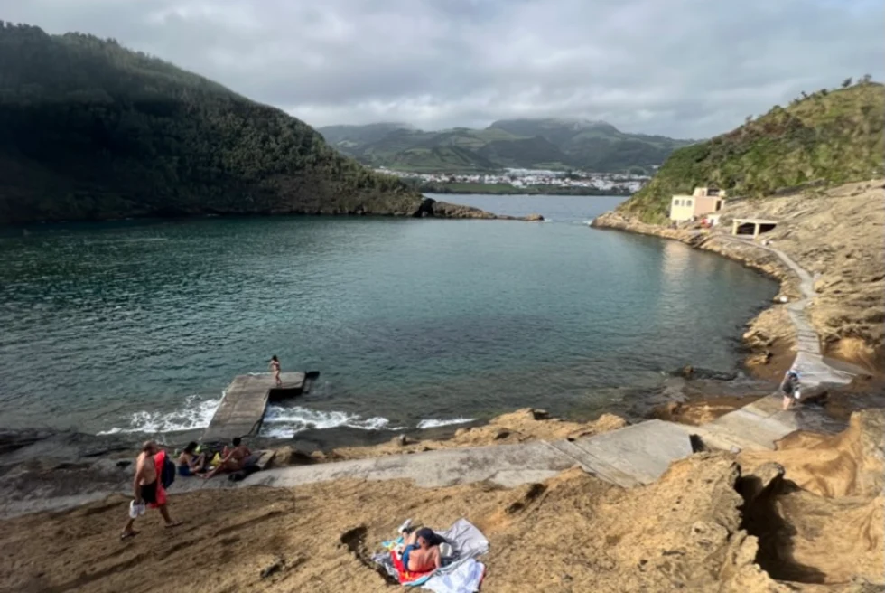 calm circular pond of water in a basin at the base of a rocky shore