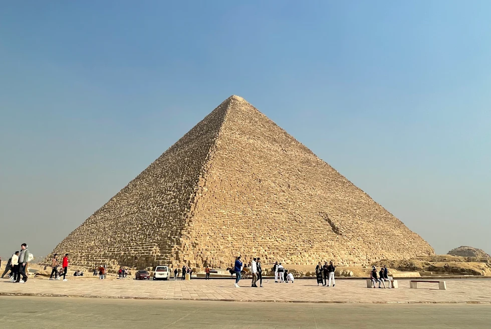 People walking around large pyramid during daytime