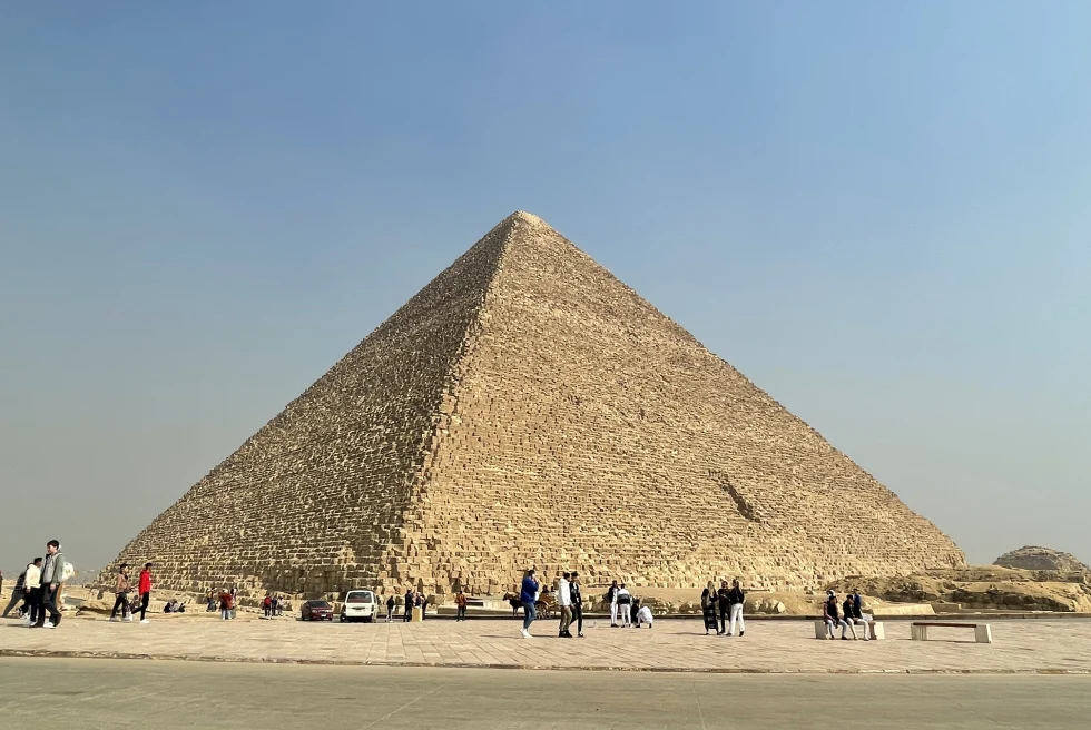 People walking around large pyramid during daytime