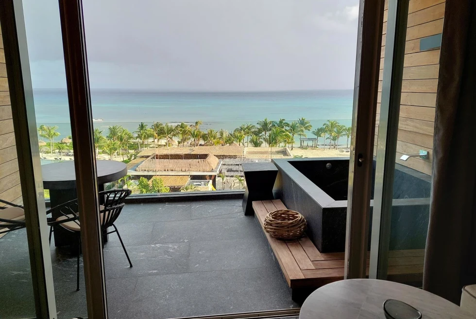 View overlooking an ocean in Mexico with a balcony that has chairs and an outdoor tub.