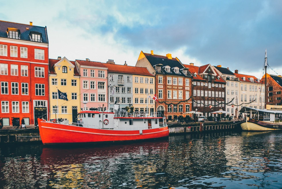 Colorful buildings on the side of a river in Copenhagen and boats floating in the river in front of buildings