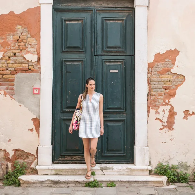 Kylie wearing a dress standing in front of a teal door and old building 