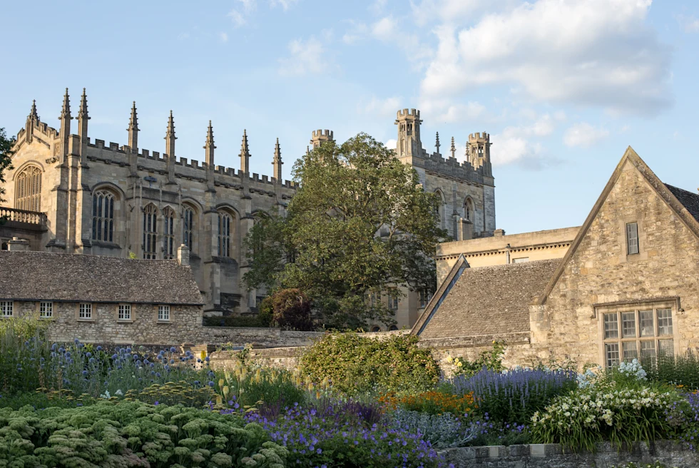 large stone building next to plants with cloudy skies