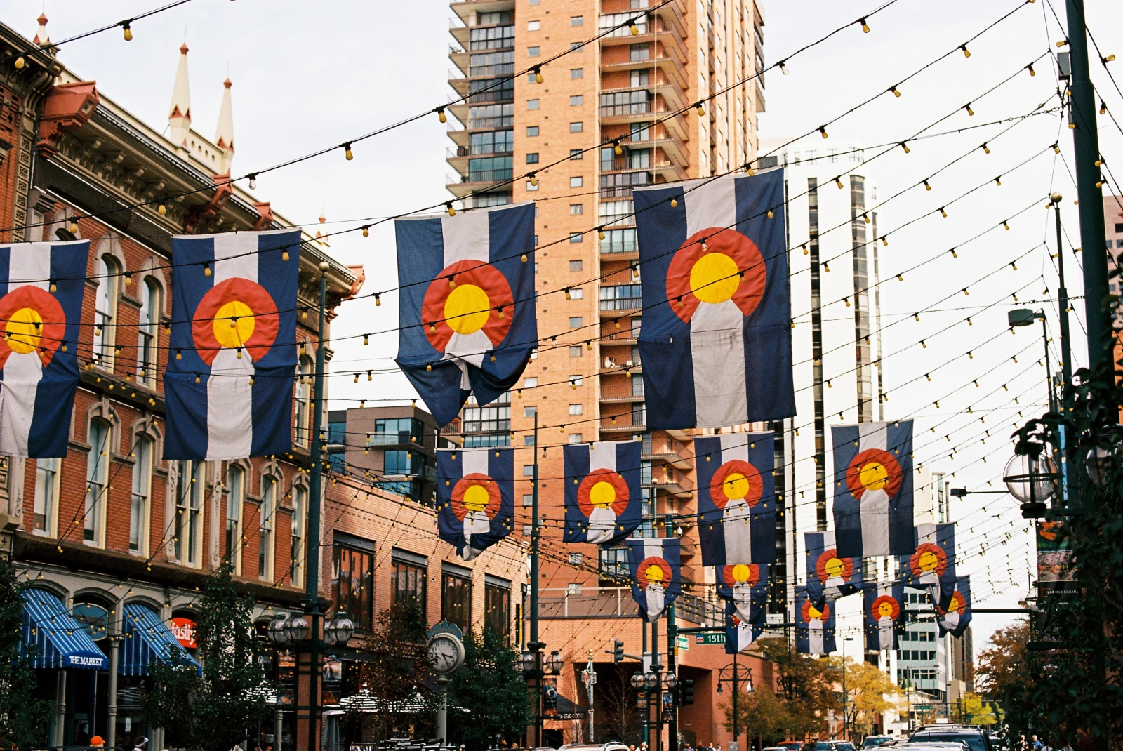 colorado flags hanging from buildings with cloudy skies