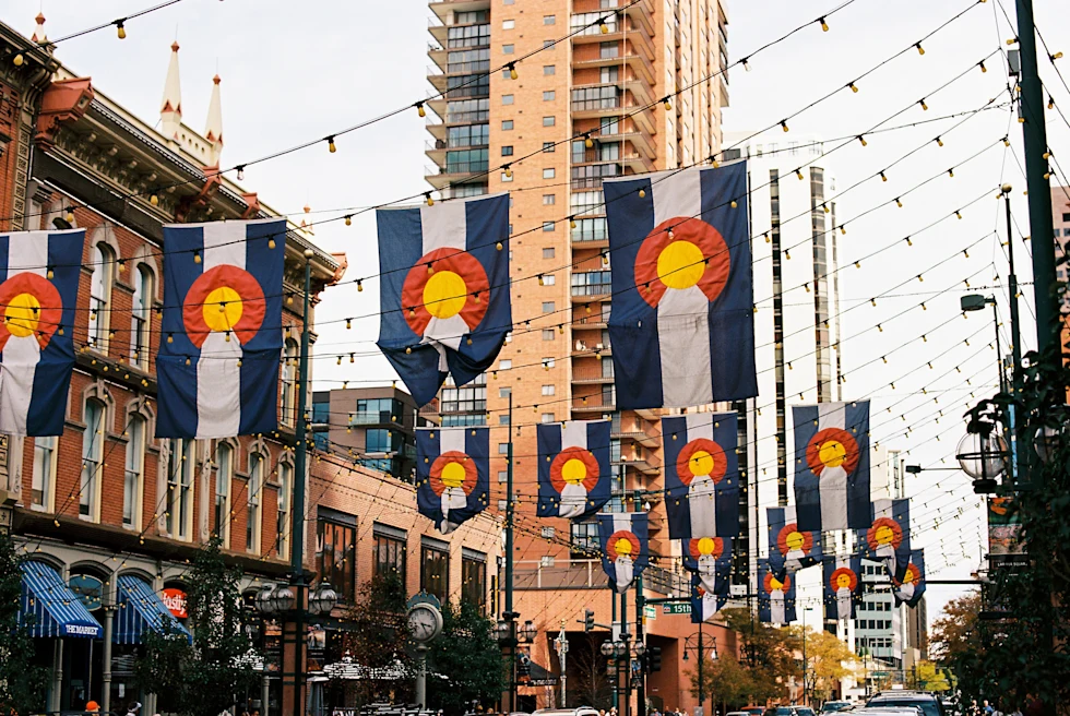 colorado flags hanging from buildings with cloudy skies