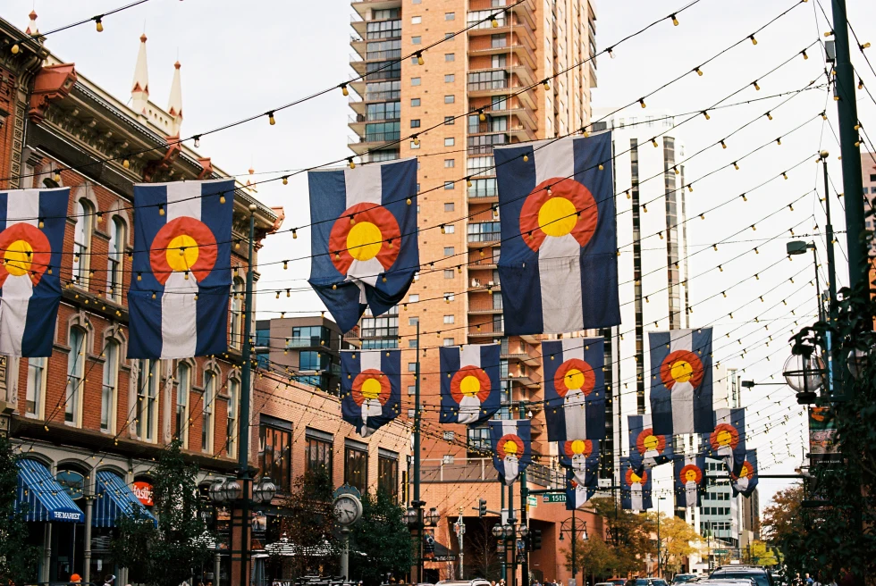 colorado flags hanging from buildings with cloudy skies