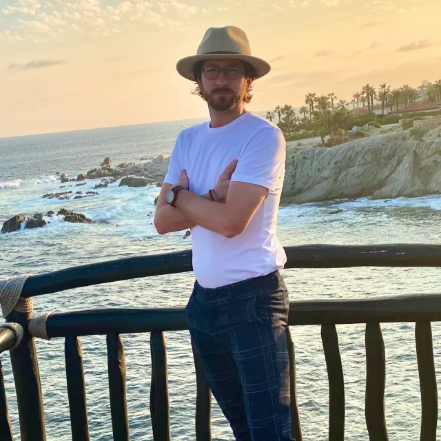 Travel advisor Kyle Ward poses in front of a stunning, rocky beach.