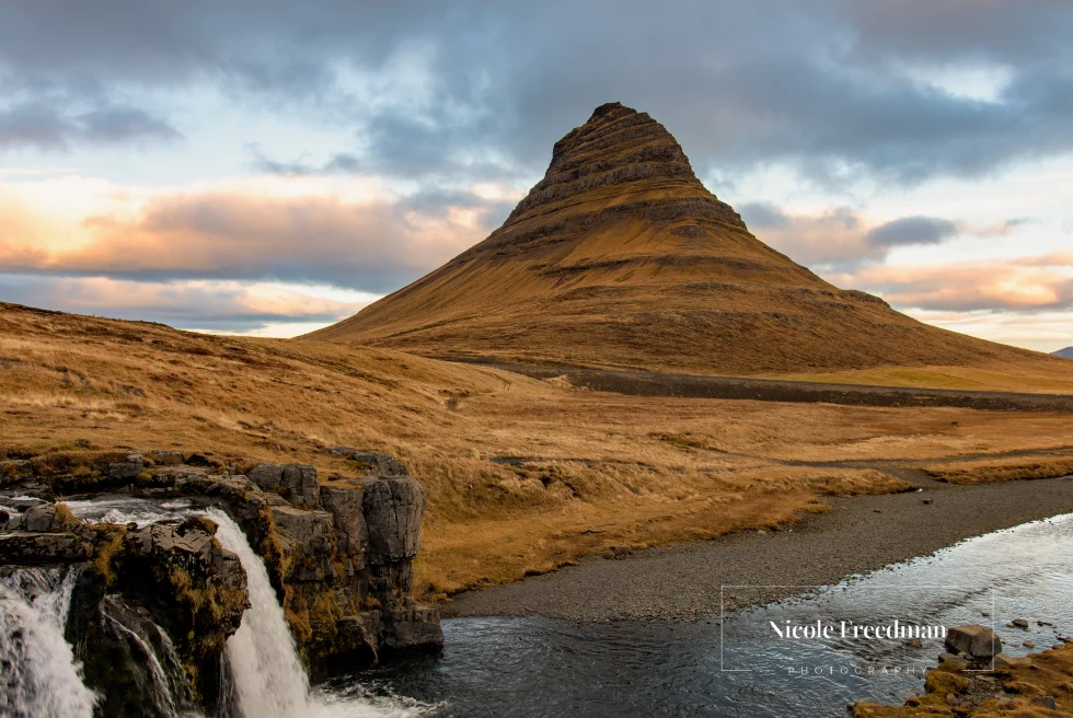 Kirkjufell mountain is surrounded by a waterfall.