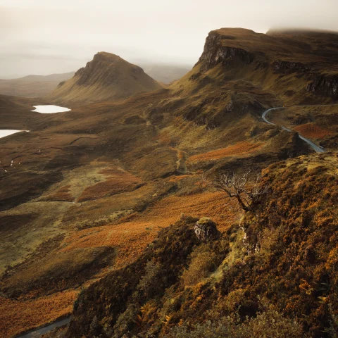 A Scottish countryside featuring hills and cliffs in fog. 