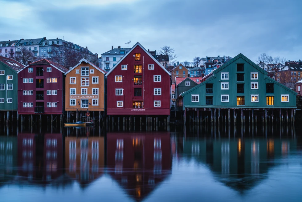 colorful houses next to body of water with cloudy skies