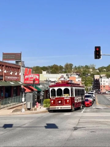 A street corner in downtown Branson, with a red trolley and quaint storefronts.