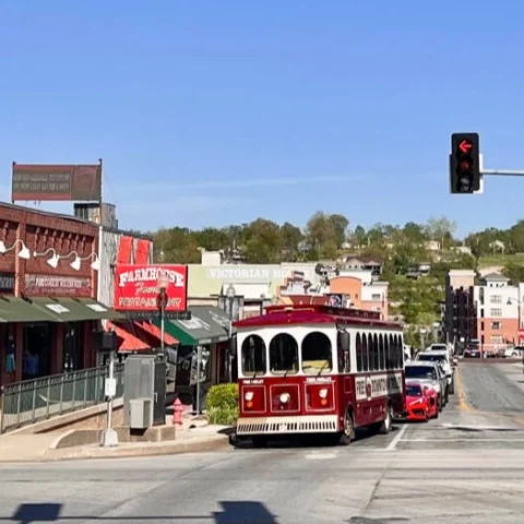 A street corner in downtown Branson, with a red trolley and quaint storefronts.