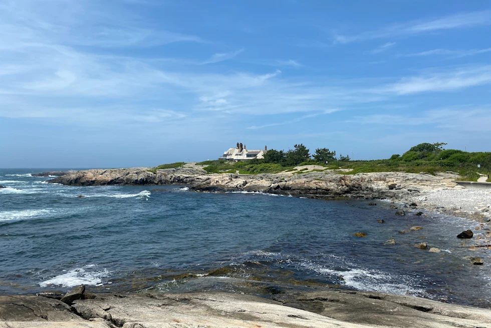 water next to rocks with house in the background