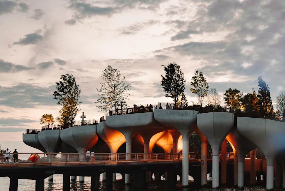 new york city trees sculptures piers with red light and cloudy skies