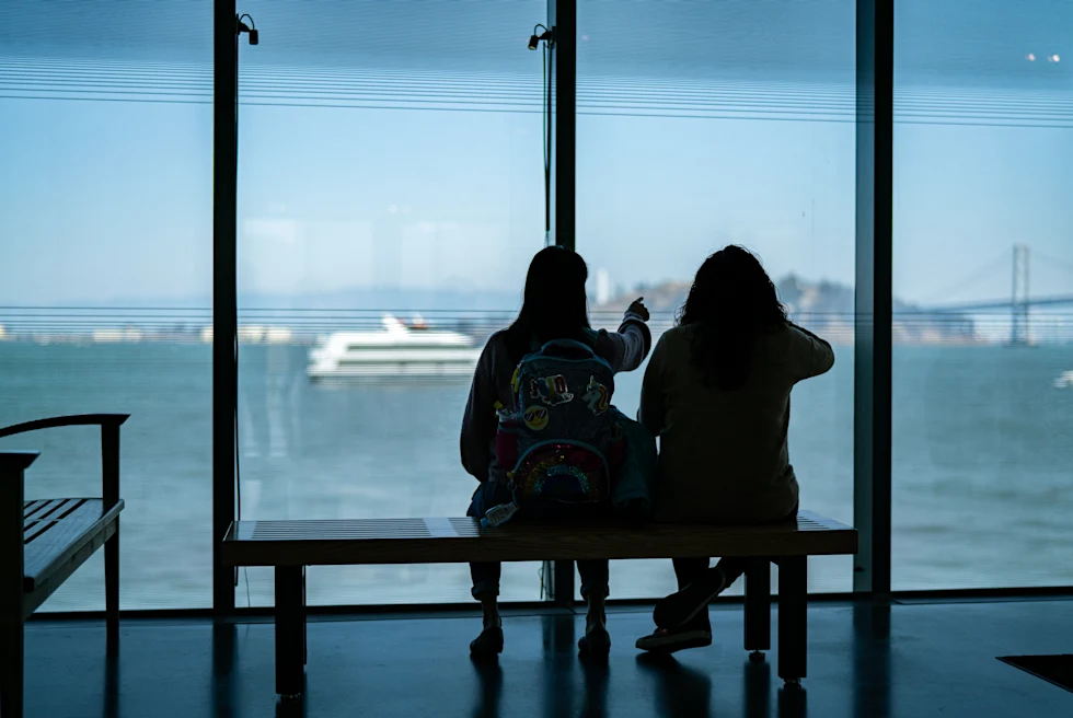two people sitting on a bench overlooking the ocean