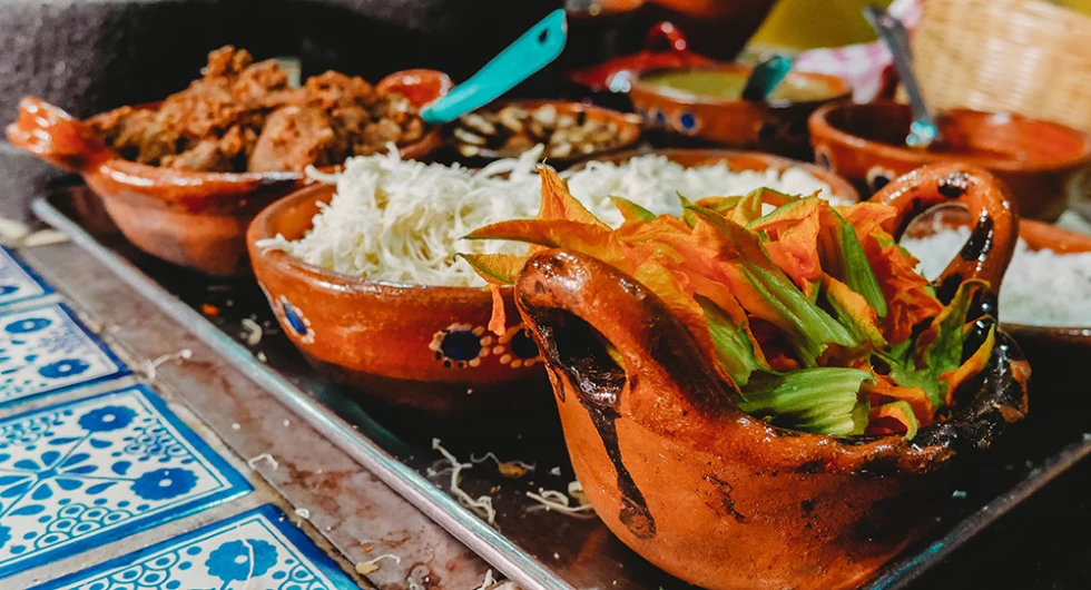 meat rice and Mexican food in colorful red clay dishes in San Miguel de Allende Mexico with blue and white flower tiles and blue metal spoons