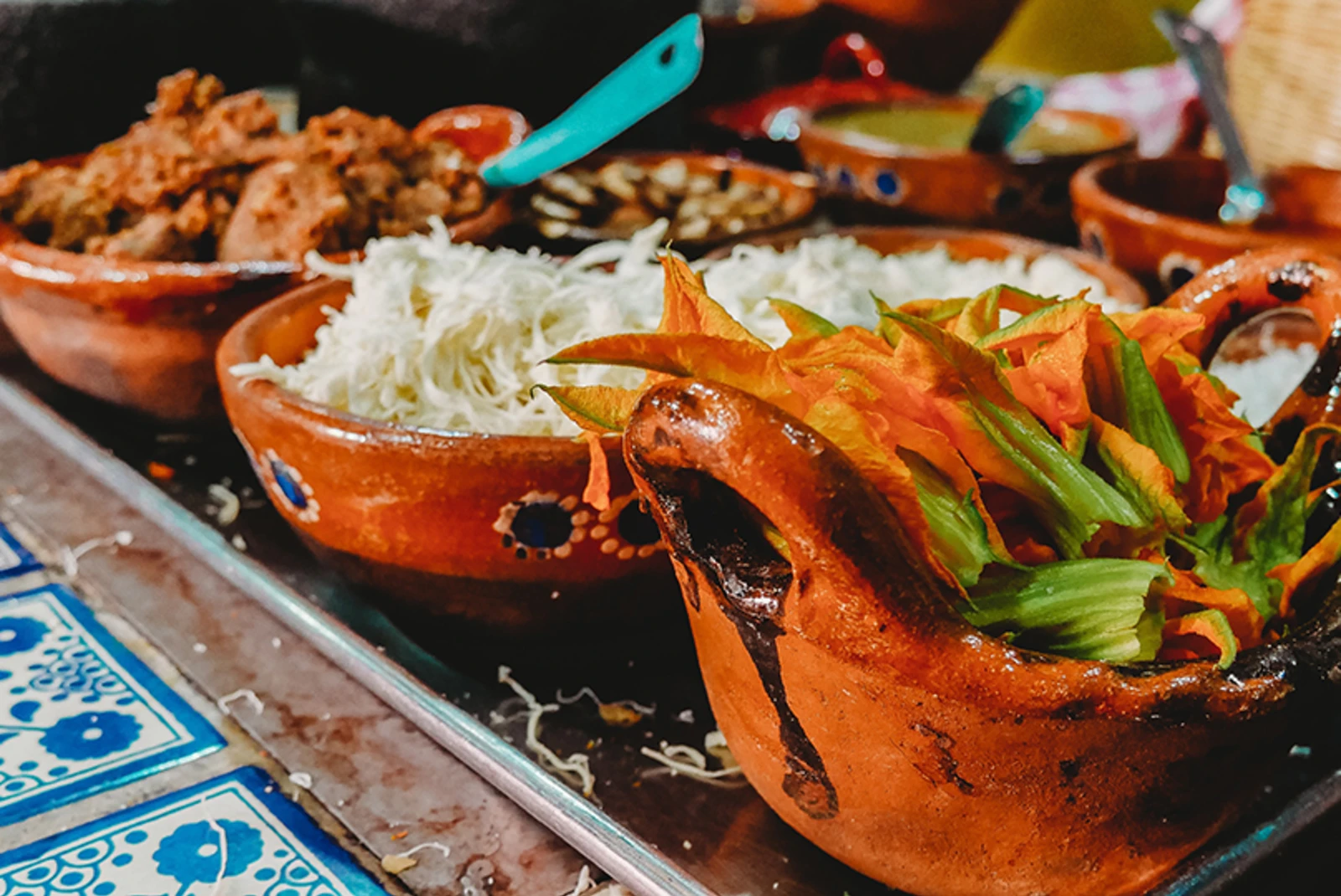 meat rice and Mexican food in colorful red clay dishes in San Miguel de Allende Mexico with blue and white flower tiles and blue metal spoons