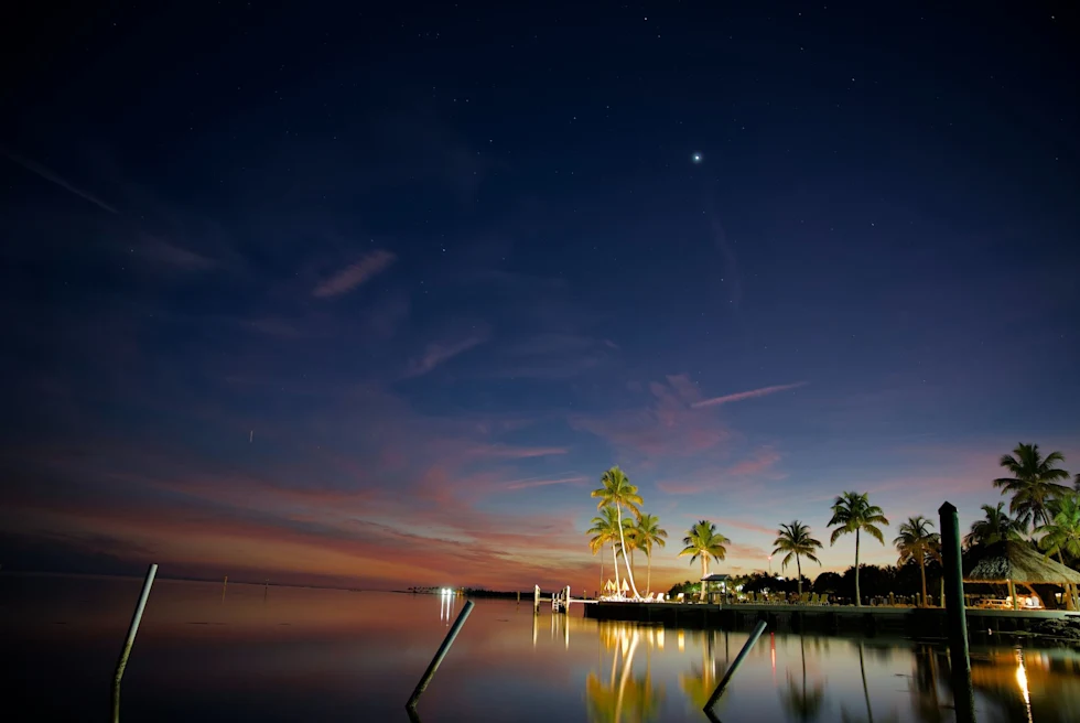 dark blue sky with pink sunset and a dock lit up by restaurant lights