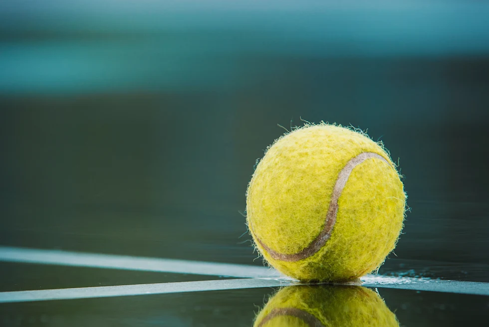 Yellowt ennis ball reflecting on tennis court in Jamaica