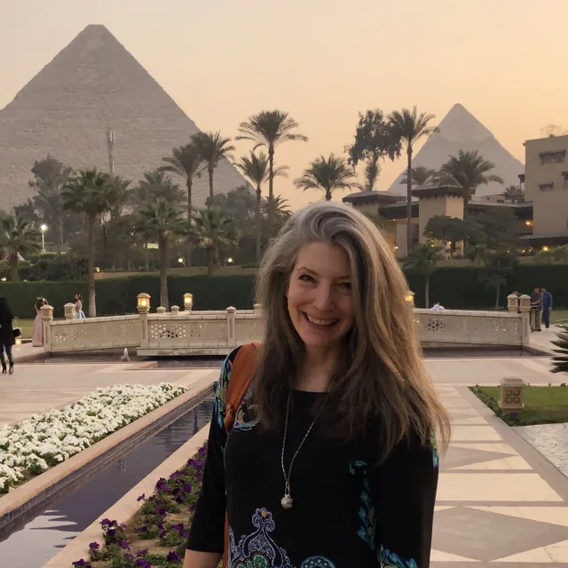 Travel Advisor Roberta Moore in a blue dress with the pyramids and palm trees behind her.