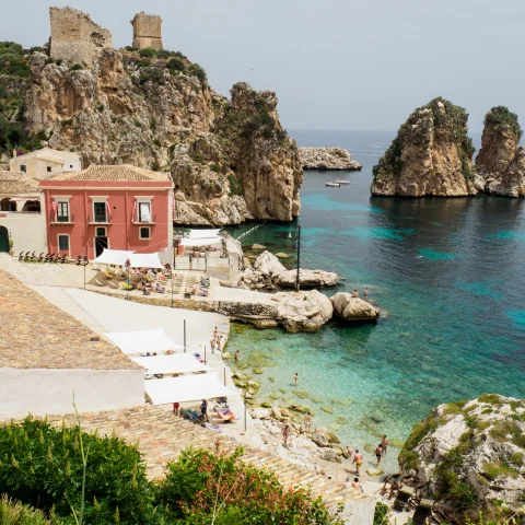 body of water next to rocks and red building during daytime