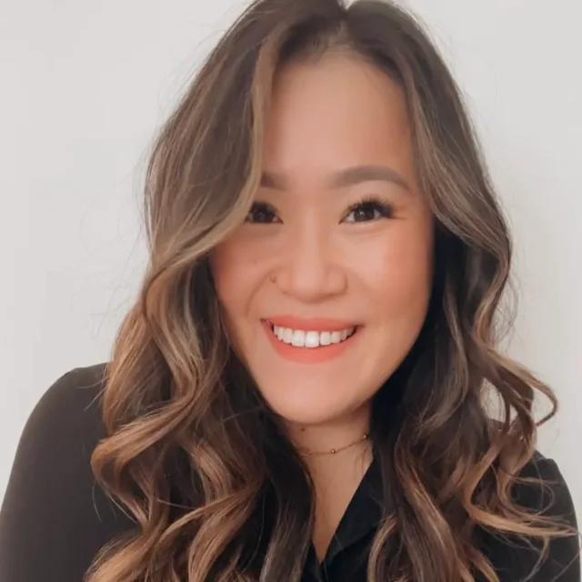 woman with long curly brown hair in a black top smiling