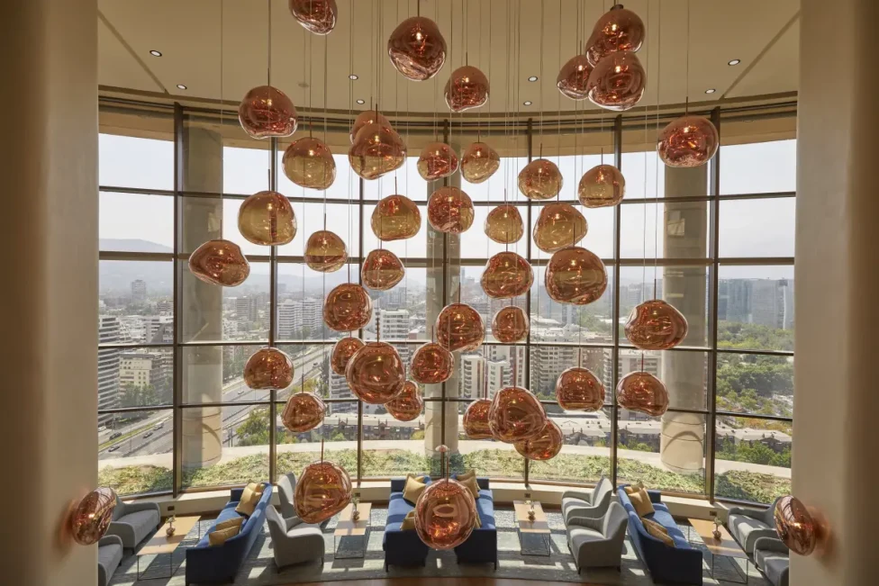 rose-gold-orb light fixtures hanging in a light-filled lobby with floor-to-ceiling windows