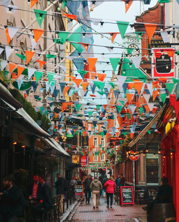 White, green and orange flags hanging over a street during daytime