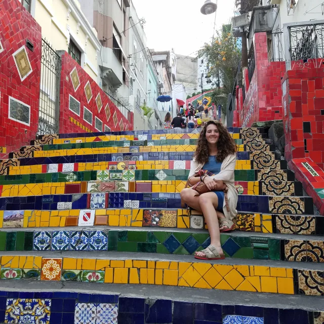 Fora travel agent sitting on colorful stairs on a cloudy day
