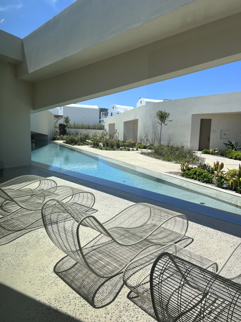 modern white lounge chairs beside a long, skinny pool