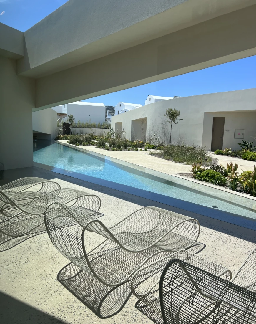modern white lounge chairs beside a long, skinny pool