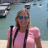Fora travel agent wearing pink shirt and sunglasses with water in the background during daytime