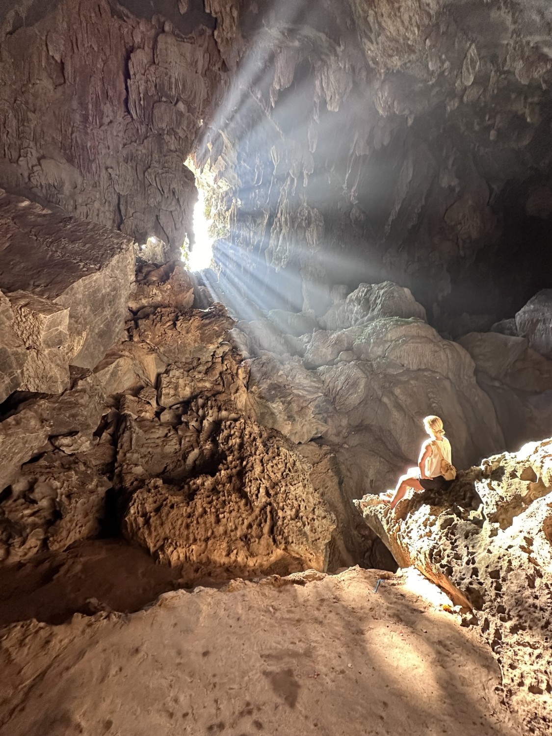 a woman sits in a sun-lit cave