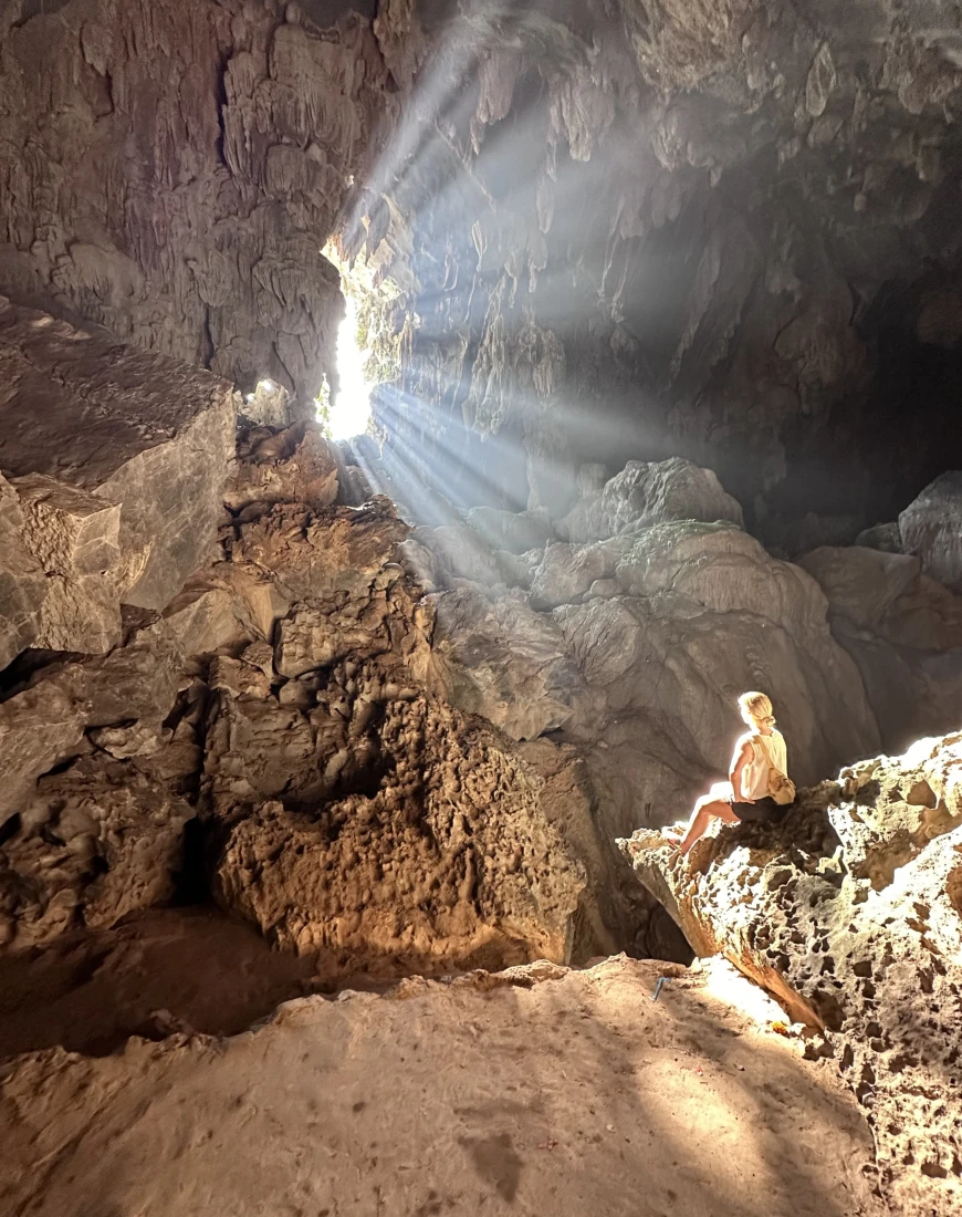 a woman sits in a sun-lit cave